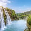 Landschap Wallgroup | Rustgevende Waterval Naar Een Rivier Fotobehang